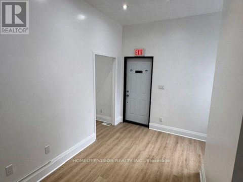 A room with a white door and a red exit sign above it.