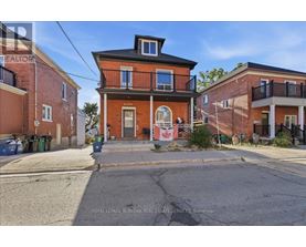 A red brick house with a balcony and a flag hanging on the front door.