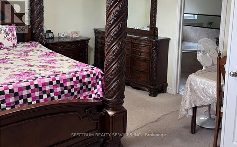 A bedroom with a bed, dresser, and mirror.