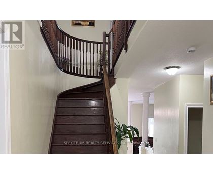 A wooden staircase with a railing and a plant on the side.
