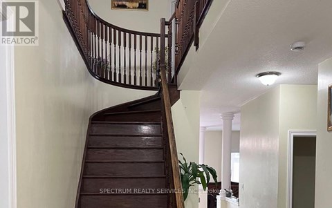 A wooden staircase with a railing and a plant on the side.