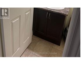 A bathroom with a white door and brown cabinets.