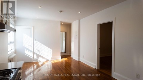 A spacious, well-lit kitchen with a stove top oven and a doorway leading to another room.