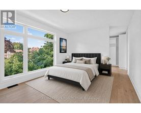 A bedroom with a large bed and a view of trees outside the window.