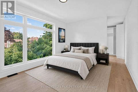 A bedroom with a large bed and a view of trees outside the window.