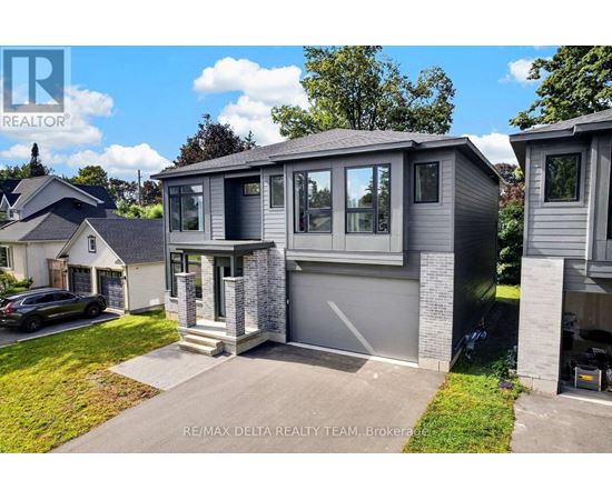 A modern house with a grey exterior and a black car parked in the driveway.