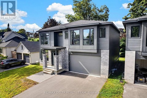 A modern house with a grey exterior and a black car parked in the driveway.