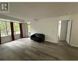 A spacious room with a black couch and wooden flooring.