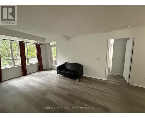A spacious room with a black couch and wooden flooring.