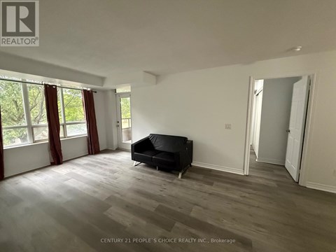 A spacious room with a black couch and wooden flooring.