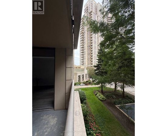 A building with a balcony overlooking a garden with a tall building in the background.