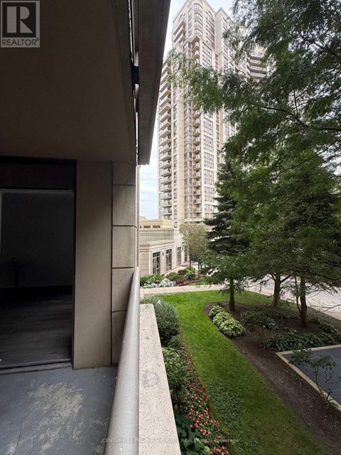 A building with a balcony overlooking a garden with a tall building in the background.