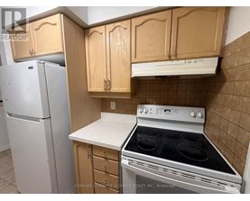 A kitchen with a white fridge, wooden cabinets and a white stove top oven.