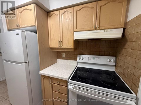 A kitchen with a white fridge, wooden cabinets and a white stove top oven.