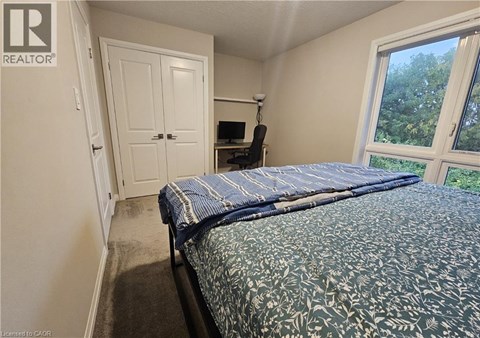 A bedroom with a bed, a chair, and a window.