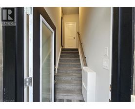 A hallway with a staircase leading to a door at the end.