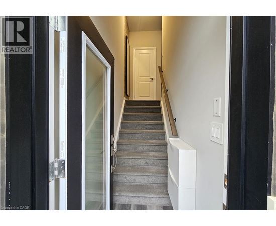 A hallway with a staircase leading to a door at the end.