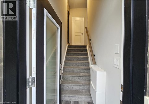 A hallway with a staircase leading to a door at the end.