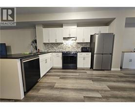 A kitchen with white cabinets and a stone backsplash.