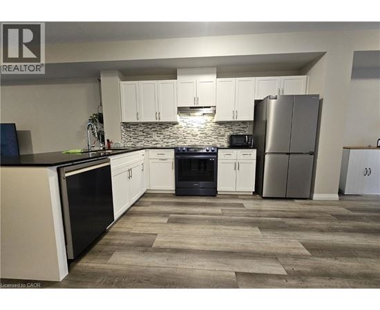 A kitchen with white cabinets and a stone backsplash.