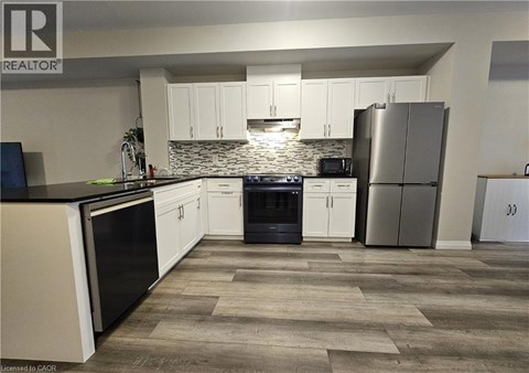 A kitchen with white cabinets and a stone backsplash.