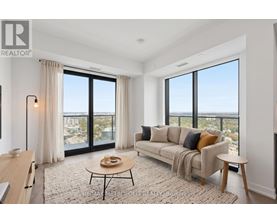 A well-lit living room with a view of the cityscape outside the large windows.