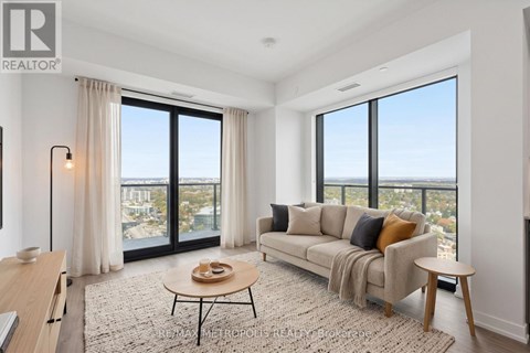 A well-lit living room with a view of the cityscape outside the large windows.