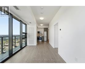 A spacious, empty room with a view of the cityscape outside the large windows.