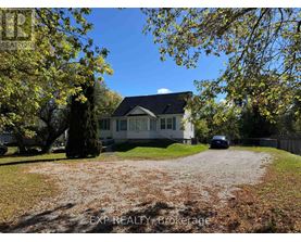 A house with a gravel driveway and trees in the background.