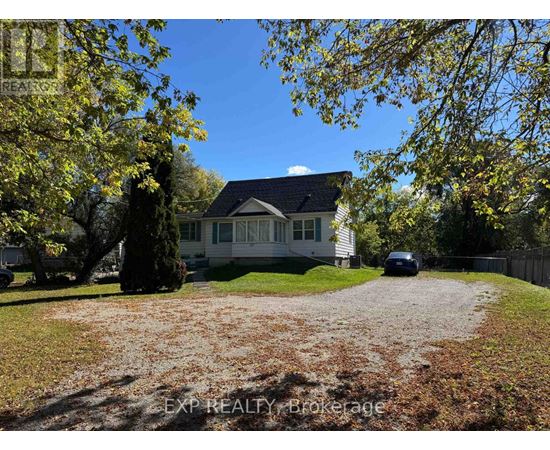 A house with a gravel driveway and trees in the background.