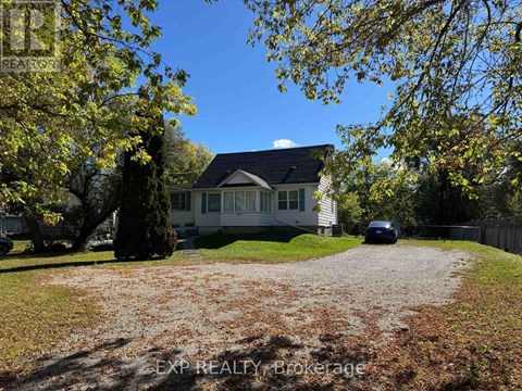 A house with a gravel driveway and trees in the background.