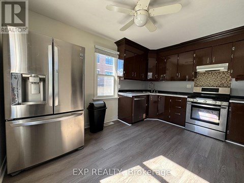 A kitchen with a stainless steel refrigerator and wooden cabinets.