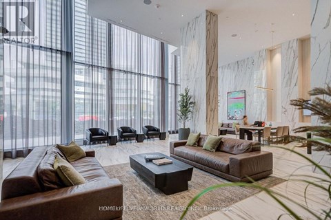 A living room with a brown couch, a coffee table, and a large window with blinds.