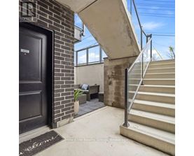 A black door with a welcome mat in front of a brick wall.