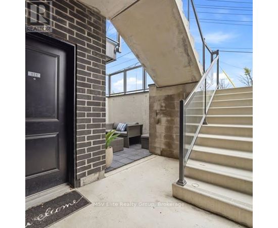 A black door with a welcome mat in front of a brick wall.