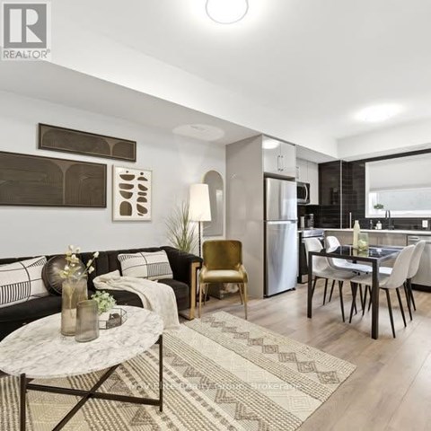 A modern living room with a black sofa, a coffee table, and a dining area with a table and chairs.