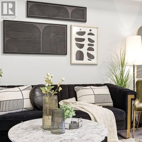 A living room with a black couch, a marble table, and two framed artworks on the wall.