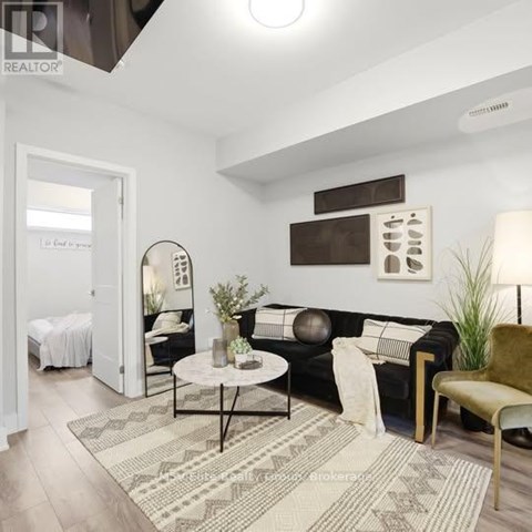 A living room with a black couch, a round table, and a rug.