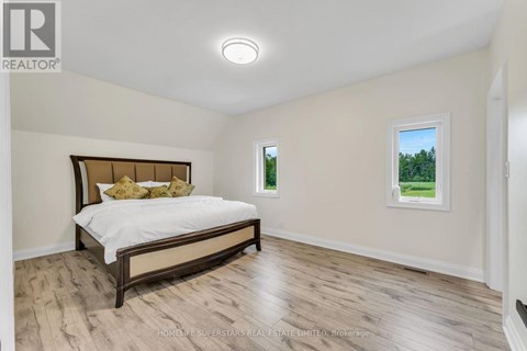 A bedroom with a bed, a window, and a wooden floor.