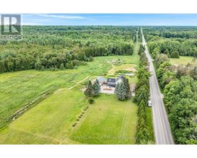 A road runs through a green field with a house on the right side.