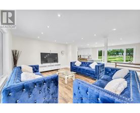 A living room with blue velvet sofas and a television.