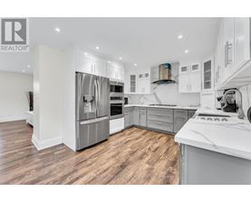 A modern kitchen with wooden floors and stainless steel appliances.