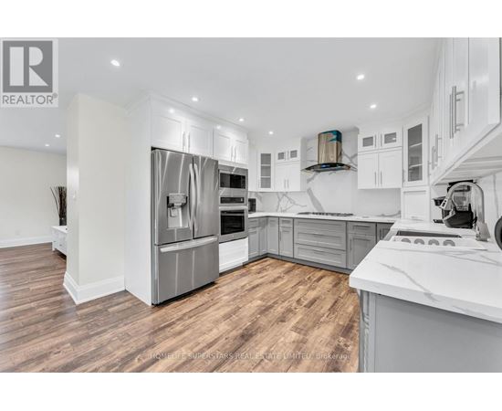 A modern kitchen with wooden floors and stainless steel appliances.