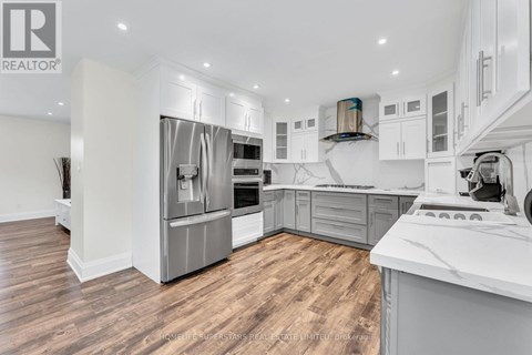 A modern kitchen with wooden floors and stainless steel appliances.