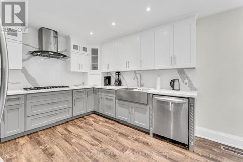 A modern kitchen with white cabinets and a wooden floor.