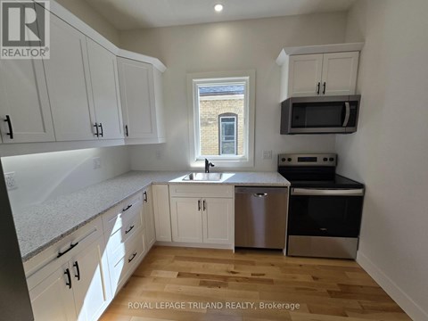 A kitchen with white cabinets and a window.