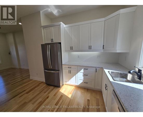 A kitchen with white cabinets and a wooden floor.