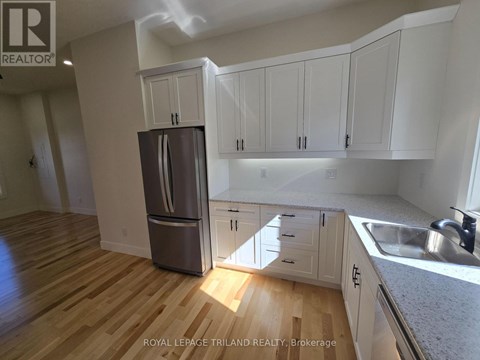 A kitchen with white cabinets and a wooden floor.