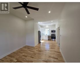 A spacious room with wooden flooring and a ceiling fan.