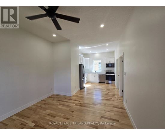 A spacious room with wooden flooring and a ceiling fan.